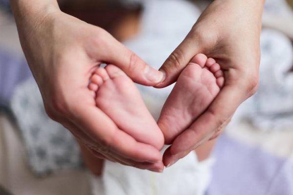 baby feet framed in heart by mother's hands