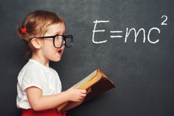 Little girl with glasses in front of blackboard