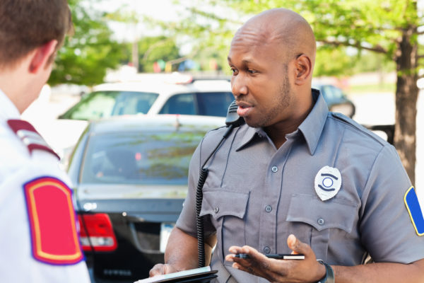 Police officer interrogating people at an emergency scene.