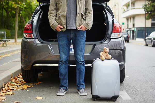 man standing next to car trunk with suitcase