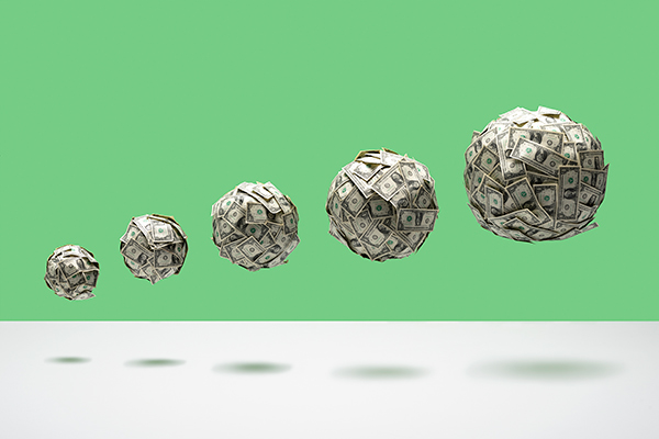 5 balls of US 1 dollar bills of various size in ascending size order, floating in mid air on white floor, green background