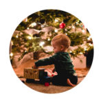 baby playing with toys underneath christmas tree