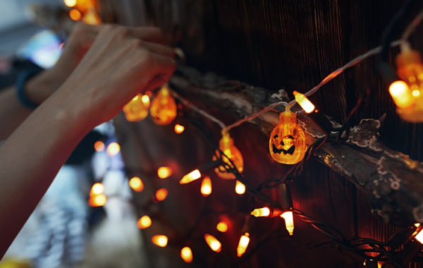 Woman hanging decorative eletric light with pumpkins. Halloween theme