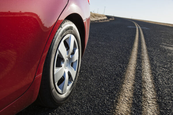 A low angle view of a rear tire on a car as it drives on the hghway.