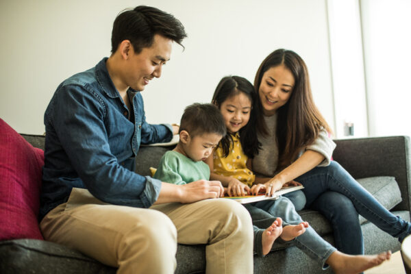 Family reading a book with young children at home