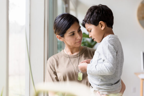As she stands by the window of their home carrying her young son, the mid adult single mother listens quietly as the boy talks about her deployment.