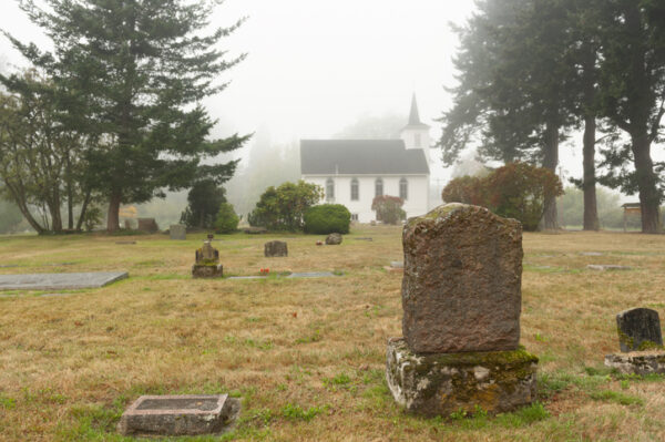 Historic cemetery dating back to the 1800's situated behind a classic white church built in 1908. This foggy morning adds atmosphere.