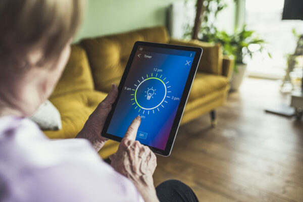 Woman adjusting timer on digital tablet at home