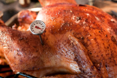 Roasted Turnkey fresh out of the oven. There is a little meat thermometer in the bird that reads 180 Roasted Turnkey fresh out of the oven. There is a little meat thermometer in the bird that reads 180?. The Fowl is Ready! This shot has a pretty narrow depth of field, focussing on the temperature gauge. The texture of the skin is fantastic and indicative of a perfectly cooked Thanksgiving turkey. The background has blurry kitchen elements in it. - A great shot for preparation cookbooks, ingredient, catalogs, chef, diet and cooking websites or magazines The bird is in a roasting Pan