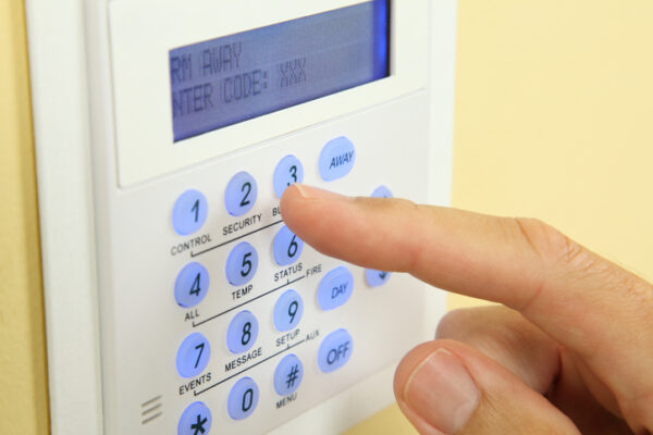 Close up of a security alarm keypad with person arming the system.