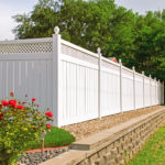 Beautiful white vinyl fence in back yard with nice landscaping in the foreground and background
