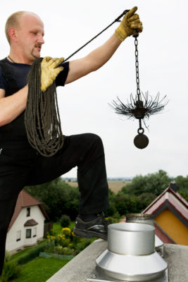 Chimney sweep at work on the roof. Manual worker. Holding up a chain with the broom to clean the chimney. XXXL (Canon Eos 1Ds Mark III)