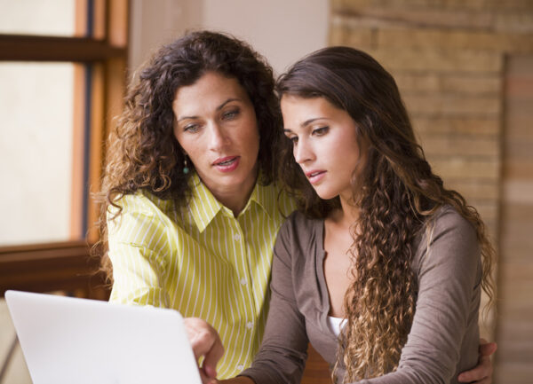 Mixed race mother and daughter using laptop together