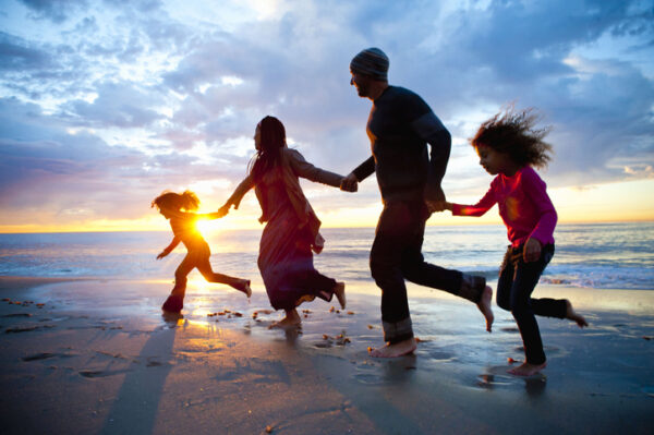 family of four having fun running on the beach