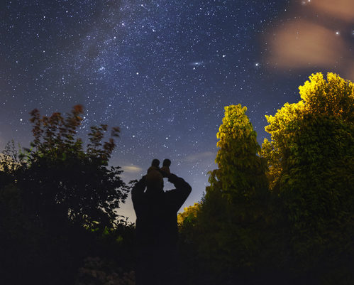 An amateur astronomer observes the Milkyway with binoculars from a rural garden in the southwest of England.