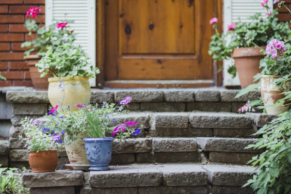 Potted plants with flowers on the steps of a house porch