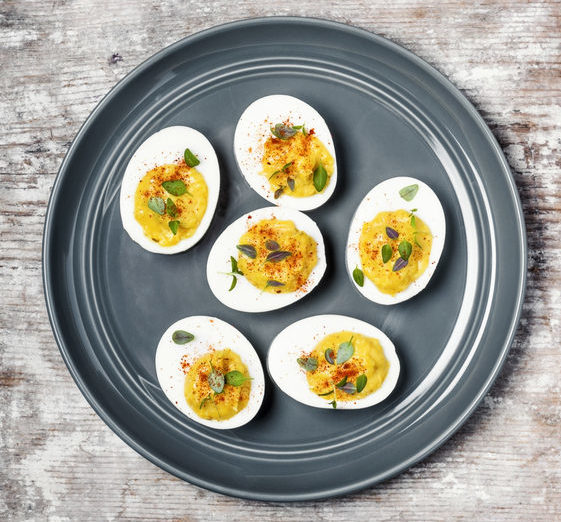 A plate of deviled eggs on wooden background