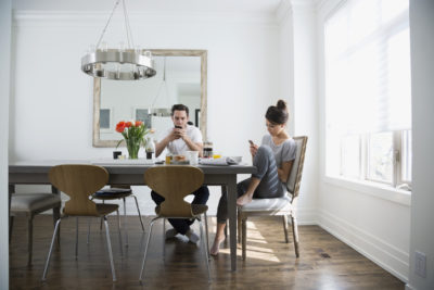 Couple texting with cell phones at breakfast dining table