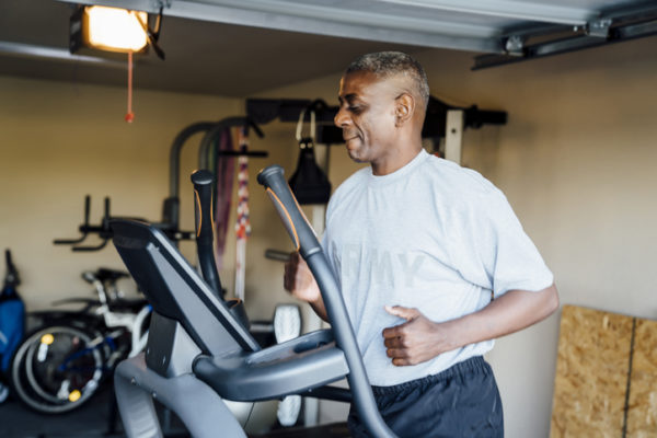 Black man running on treadmill in garage