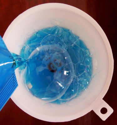 Close-Up Of Blue Dishwashing Liquid Being Poured In Funnel