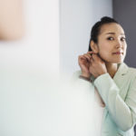 A business woman preparing for work, dressing and putting on jewelry.