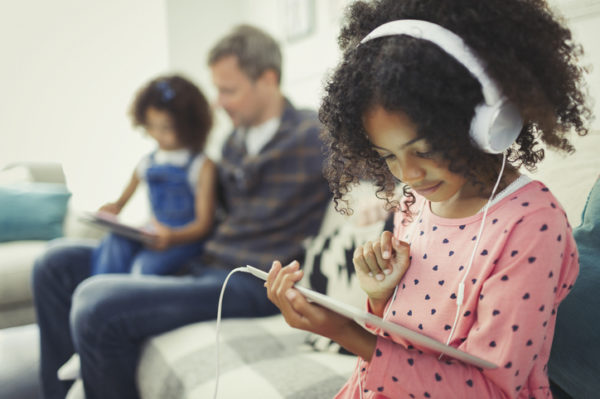 Girl with headphones using digital tablet on sofa