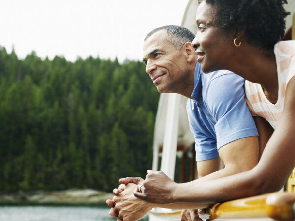 Mature couple on deck of yacht looking at view, smiling