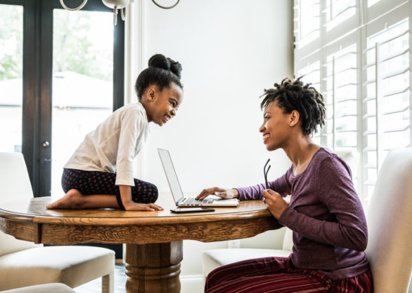 Mother working on laptop, daughter on table