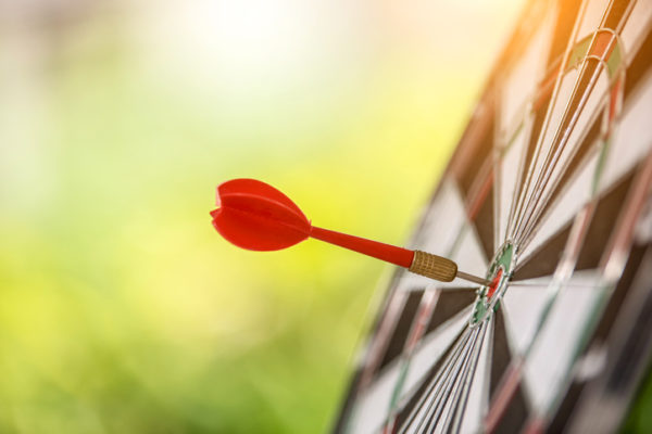 Dart arrow hitting in the target center of dartboard