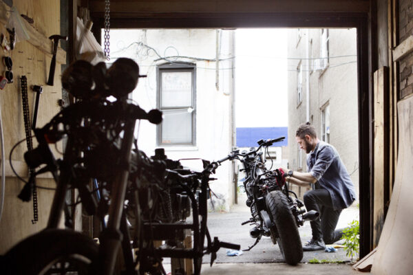 Side view of man repairing motorcycle outside workshop