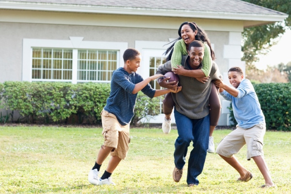 african-american family playing football in backyard