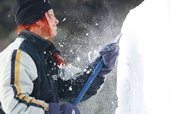 Young woman easily creating a snow sculpture