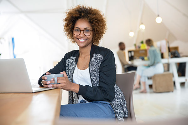 Woman drinking coffee at laptop