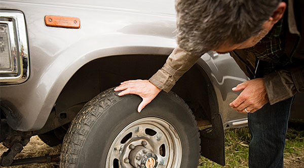 Checking a car's tires for wear and tear