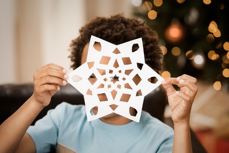 boy holding up paper snowflake
