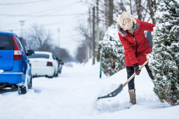 woman shoveling snow by the road