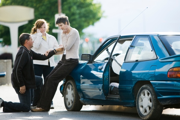 people helping a woman after a car accident